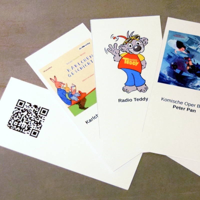 The QR cards for the AudioSphere player. They are placed on top of the case with the cover picture facing up. On the backside is a QR code that tells the player where to find the MP3 files.