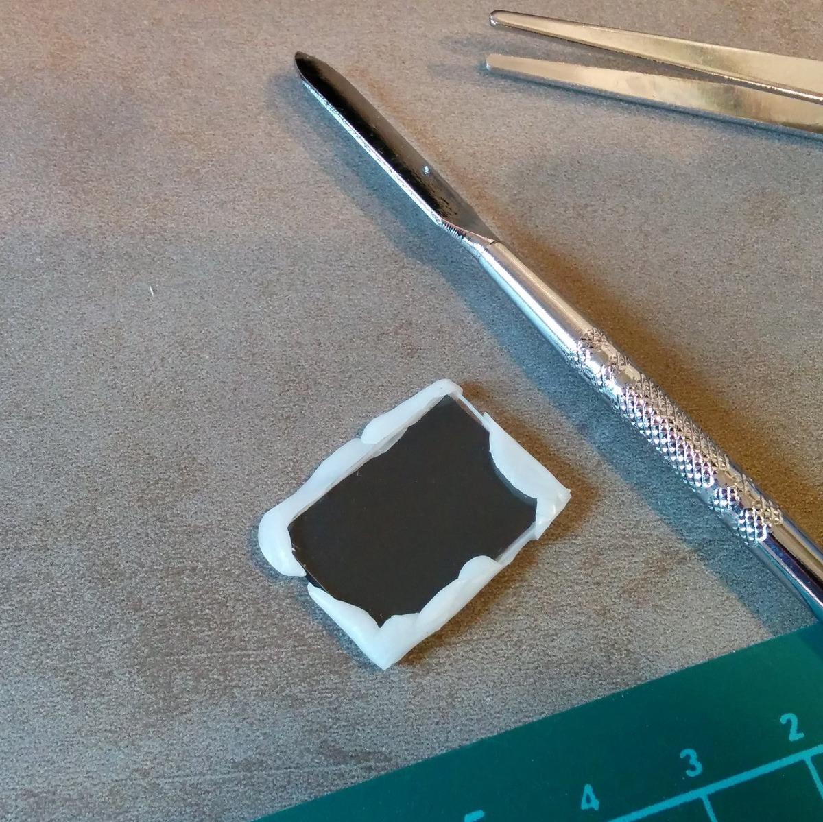 Vor das Stück aus der Diskette kommt noch ein Stück Acrylglas, damit nicht der erste Finger, der die Konstruktion testet, gleich durchsticht. Zusammengehalten werden die beiden Zeile mit Polymorph.